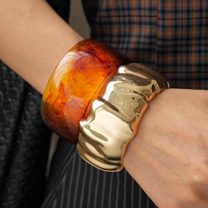Detail view of retro amber resin marble bangle and irregular wavy gold metal bracelet set