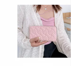 Detail of pink woven leather long wallet held by model showing intricate texture