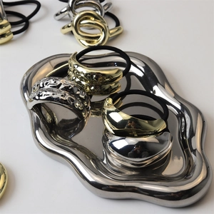 Sleek liquid metal hair ties in gold and silver finish on a stylish chrome tray
