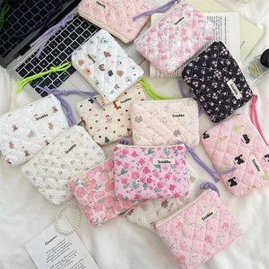 Flat lay of floral and animal pattern quilted cotton makeup pouches with woven handle