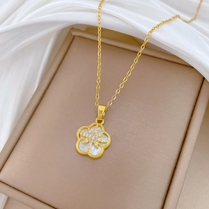 Macro shot of gold floral necklace with white shell inlay and zircon star on silk