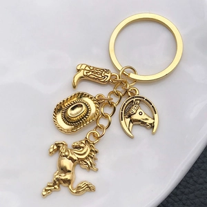 Close-up of golden metal western keychain with cowboy hat, boot, and horse charms on ceramic