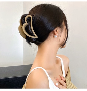 Side view of a large cream resin heart hair claw clip on a woman's hair with a soft look