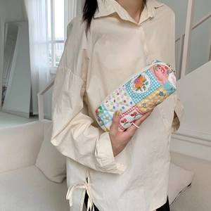 Floral patchwork cosmetic bag held by a person showing the quilted texture and patterns