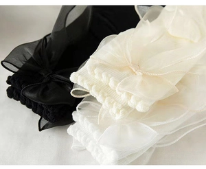 Close-up of knit cotton socks with organza lace bows and ruffled edges in black and white