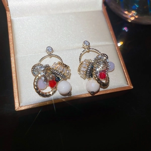 Macro shot of ethnic style gold earrings with zircon, pearls and colorful beads