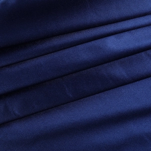 Détail du tissu satiné bleu foncé montrant une texture lisse et des reflets élégants
