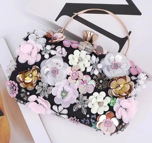 Close-up of luxury evening clutch bag with 3D colorful floral petals and metallic handle