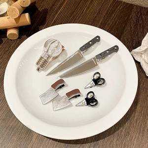 Creative miniature kitchen knife and glowing bulb hair clips displayed on a white plate