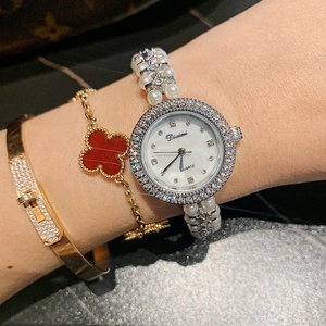 Detail of round shell dial watch for women with rhinestone bezel and pearl strap
