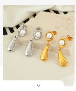 Detail of minimalist 18k plated water drop pearl earrings on a stone display background