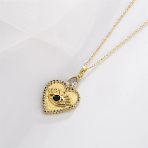 Detailed close-up of golden heart evil eye necklace with colorful crystals on white silk