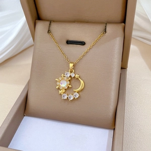 Macro view of gold crescent moon and opal sun pendant with pavé zircon details
