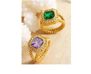 Macro detail of gold braided rings with emerald and amethyst square-cut stones