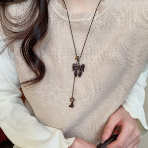 Détail du collier noeud léopard avec perles sur cordon en cuir marron sur tricot