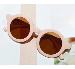 Detail view of pink round frame sunglasses with brown UV lenses on a magazine background
