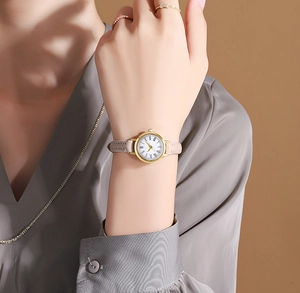 Detail of elegant gold quartz watch with white Roman dial and thin pink leather strap