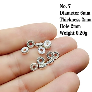 Macro shot of 6mm silver gear spacer beads on fingertips showing small scale and size