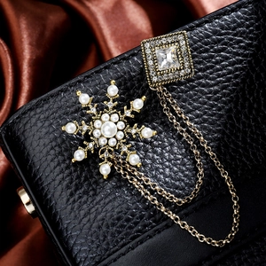Close-up of snowflake brooch with pearls and crystals on black leather background
