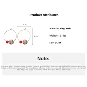 Detail view of 3cm resin ball earrings with blue floral patterns and red beads