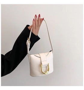 Detailed view of cream saddle bag with premium gold horseshoe metal buckle and leather strap
