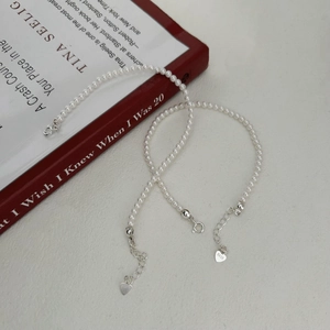 Elegant S925 sterling silver pearl bracelet with heart charm on a red book cover