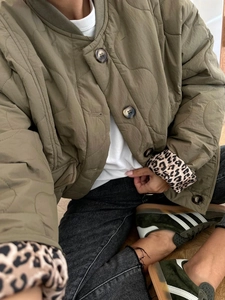 Close-up of olive quilted jacket with brown buttons and leopard print cuffs detailing