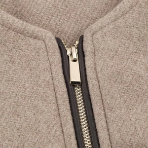 Détail de la fermeture éclair en métal et bordure en cuir sur veste en laine beige