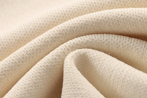 Macro detail of high-density cream knit fabric showing soft texture and premium weave