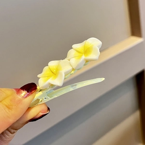 Close-up of sweet frangipani flower duckbill hair clips with white and yellow resin petals