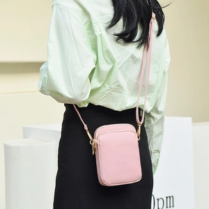 Pink mini nylon crossbody phone bag with multi-layer zippers worn by a model