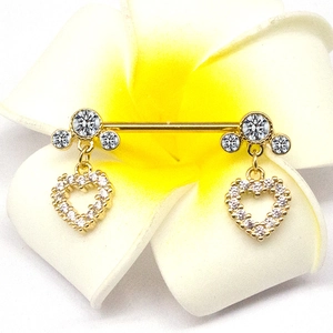 Golden heart pendant nipple ring with zircon clusters displayed on a frangipani flower
