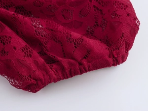 Gros plan détaillé du tissu en dentelle rouge foncé avec motifs floraux et bords plissés