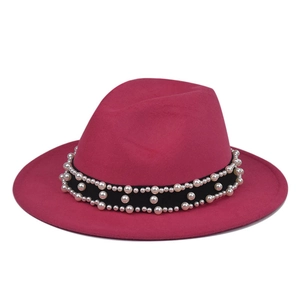 Close-up of fuchsia wool fedora hat featuring elegant faux pearl accents on a black band