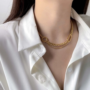 Close-up of layered gold geometric link necklace on model wearing white silk shirt
