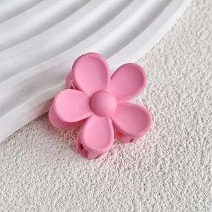 Close-up of a matte pink flower hair claw clip with a minimalist six-petal design