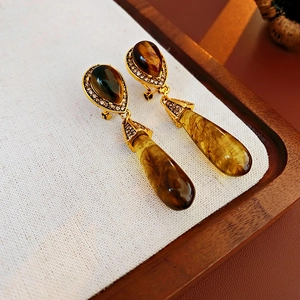 Macro view of vintage gold earrings featuring teardrop faux tiger eye and crystals