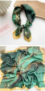 Close-up of emerald and gold marble pattern silk scarf tied and flat on a wood tray