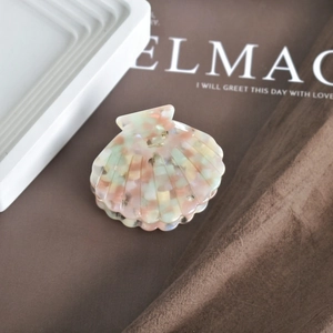 Close-up of shell-shaped acetate hair claw clip with colorful marble pattern and metal spring