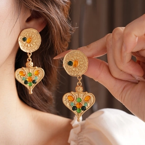 Detail of vintage gold tassel earrings featuring heart floral patterns and multi-color gems