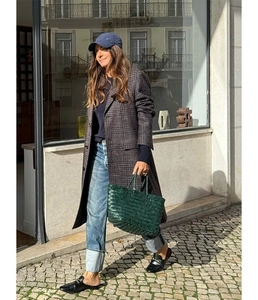 Dark green woven leather tote bag paired with an autumn checkered coat in urban street view
