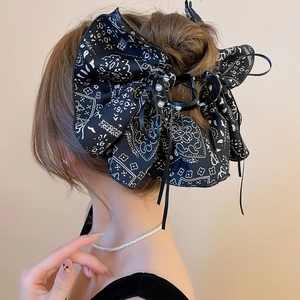 Detail view of large black paisley print bow hair claw clip with pearl accents on hair