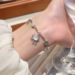 Detailed view of silver beaded bracelet with oval gemstone and leaf charm on a woman wrist