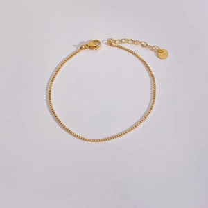 Detail of golden stainless steel box chain bracelet with lobster clasp and tag