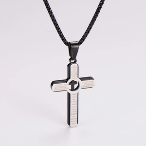 Detail of silver and black cross pendant featuring engraved Lord's Prayer text