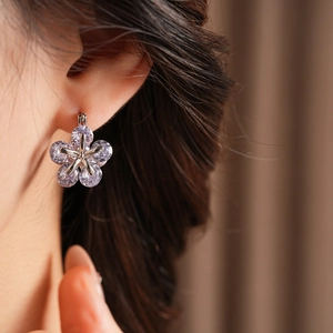 Gros plan sur les boucles d'oreilles fleur en argent avec zircons violets et clairs