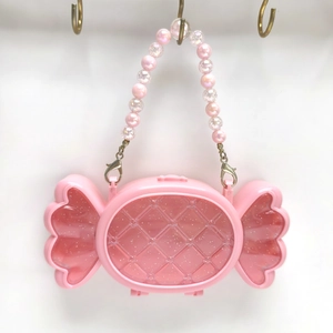 Dettaglio della borsa portagioielli rosa a forma di caramella con manico di perle