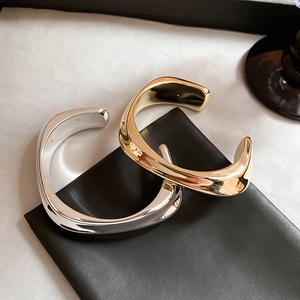 Gros plan de bracelets métalliques au design fluide en finitions or et argent polies