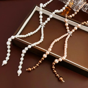 Detailed view of white and champagne pearl necklaces with sparkling diamond-set silver clasps