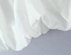 Detail of white satin fabric showing soft folds and smooth glossy texture of the top